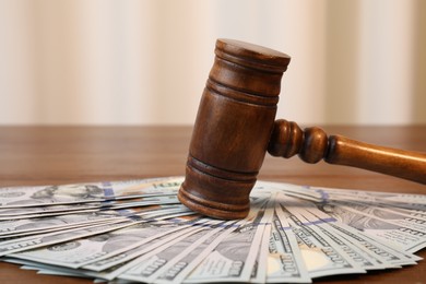 Alimony. Judge's gavel and pile of money on wooden table, closeup