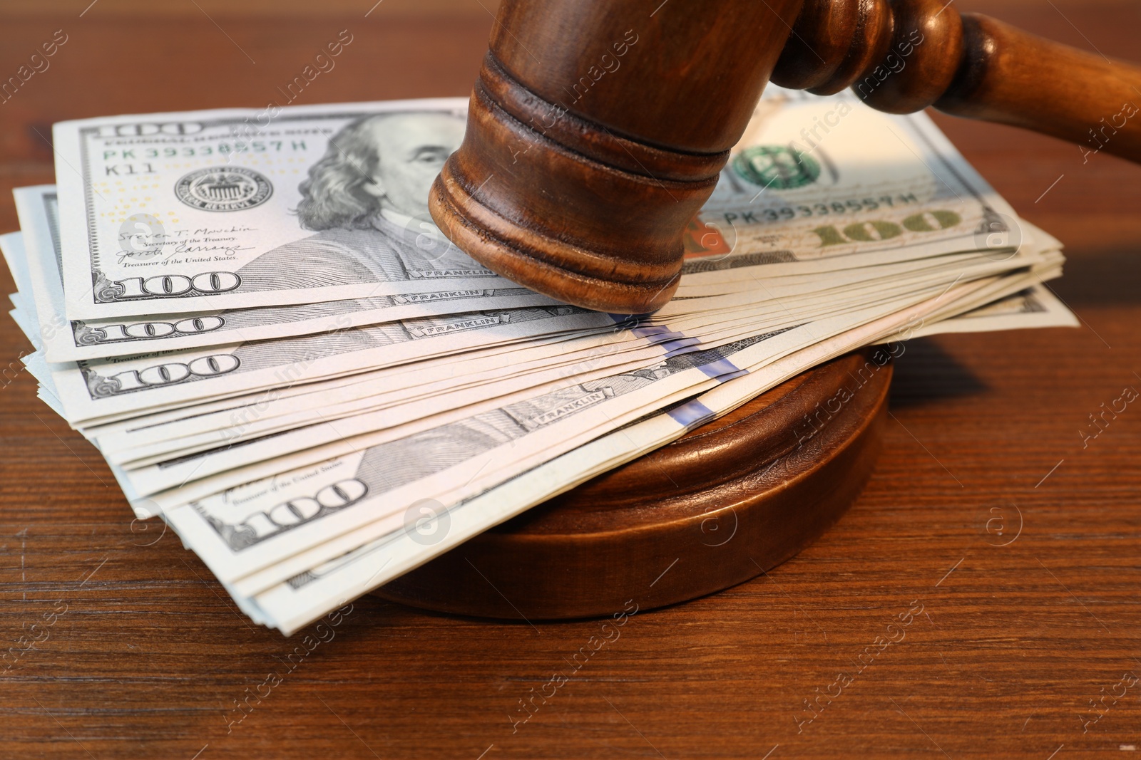 Photo of Alimony. Money between judge's gavel and sound block on wooden table, closeup