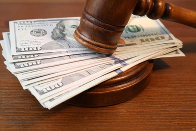 Alimony. Money between judge's gavel and sound block on wooden table, closeup