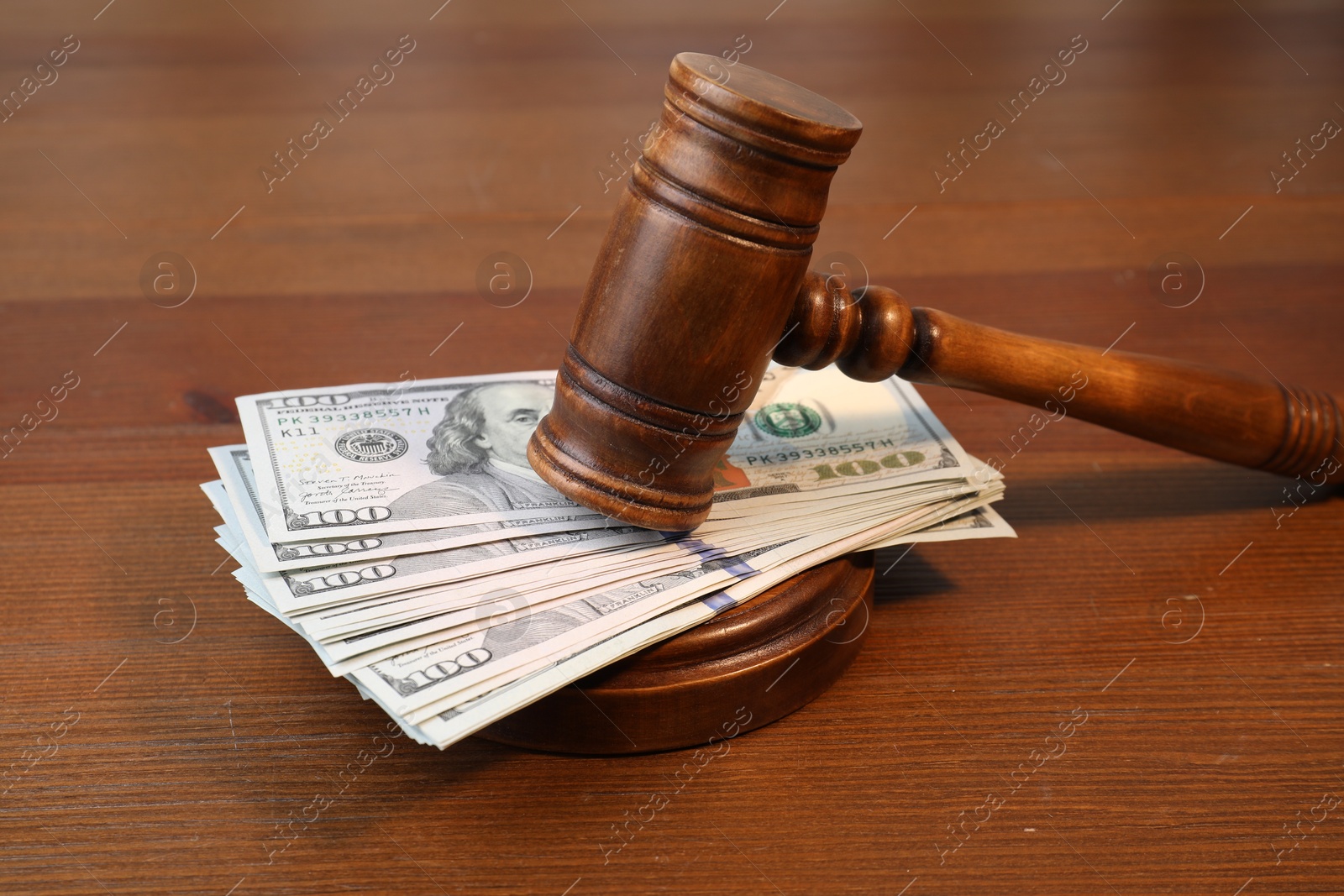 Photo of Alimony. Money between judge's gavel and sound block on wooden table, closeup