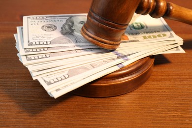 Alimony. Money between judge's gavel and sound block on wooden table, closeup