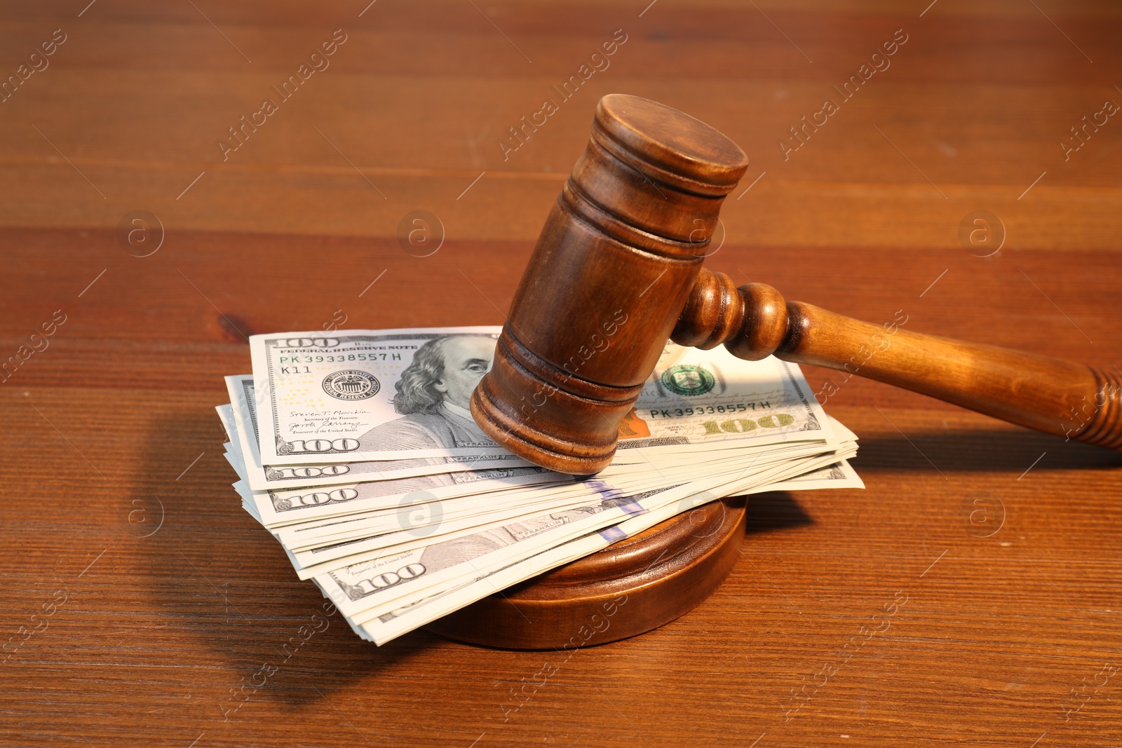 Photo of Alimony. Money between judge's gavel and sound block on wooden table, closeup