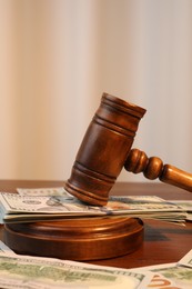 Alimony. Judge's gavel and sound block surrounded by money on wooden table, closeup