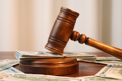 Alimony. Judge's gavel and sound block surrounded by money on wooden table, closeup