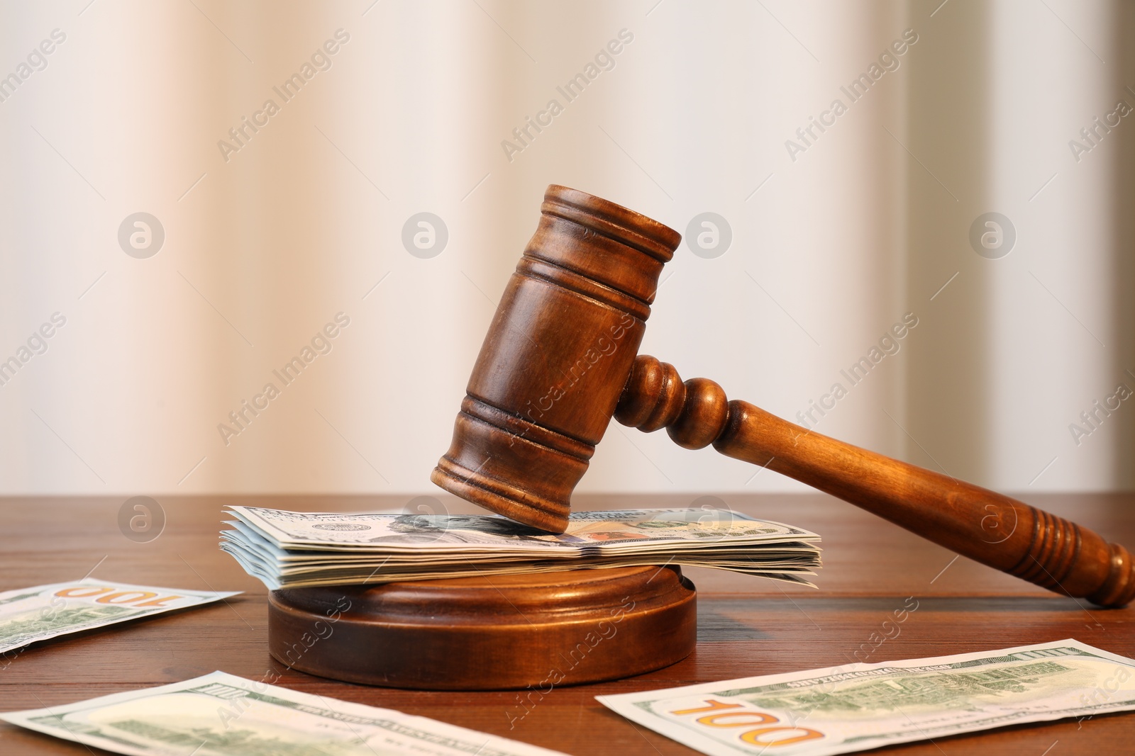 Photo of Alimony. Judge's gavel and sound block surrounded by money on wooden table, closeup