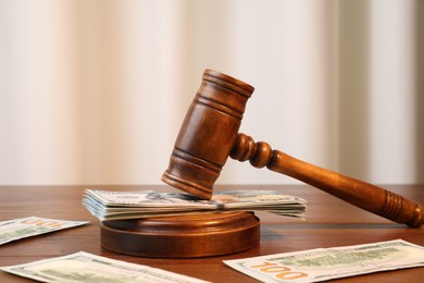 Alimony. Judge's gavel and sound block surrounded by money on wooden table, closeup