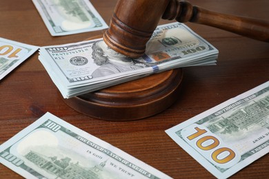 Alimony. Judge's gavel and sound block surrounded by money on wooden table, closeup