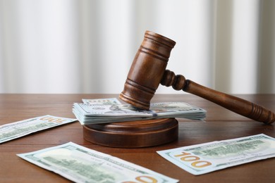 Photo of Alimony. Money, judge's gavel and sound block on wooden table, closeup