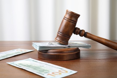 Photo of Alimony. Money, judge's gavel and sound block on wooden table, closeup