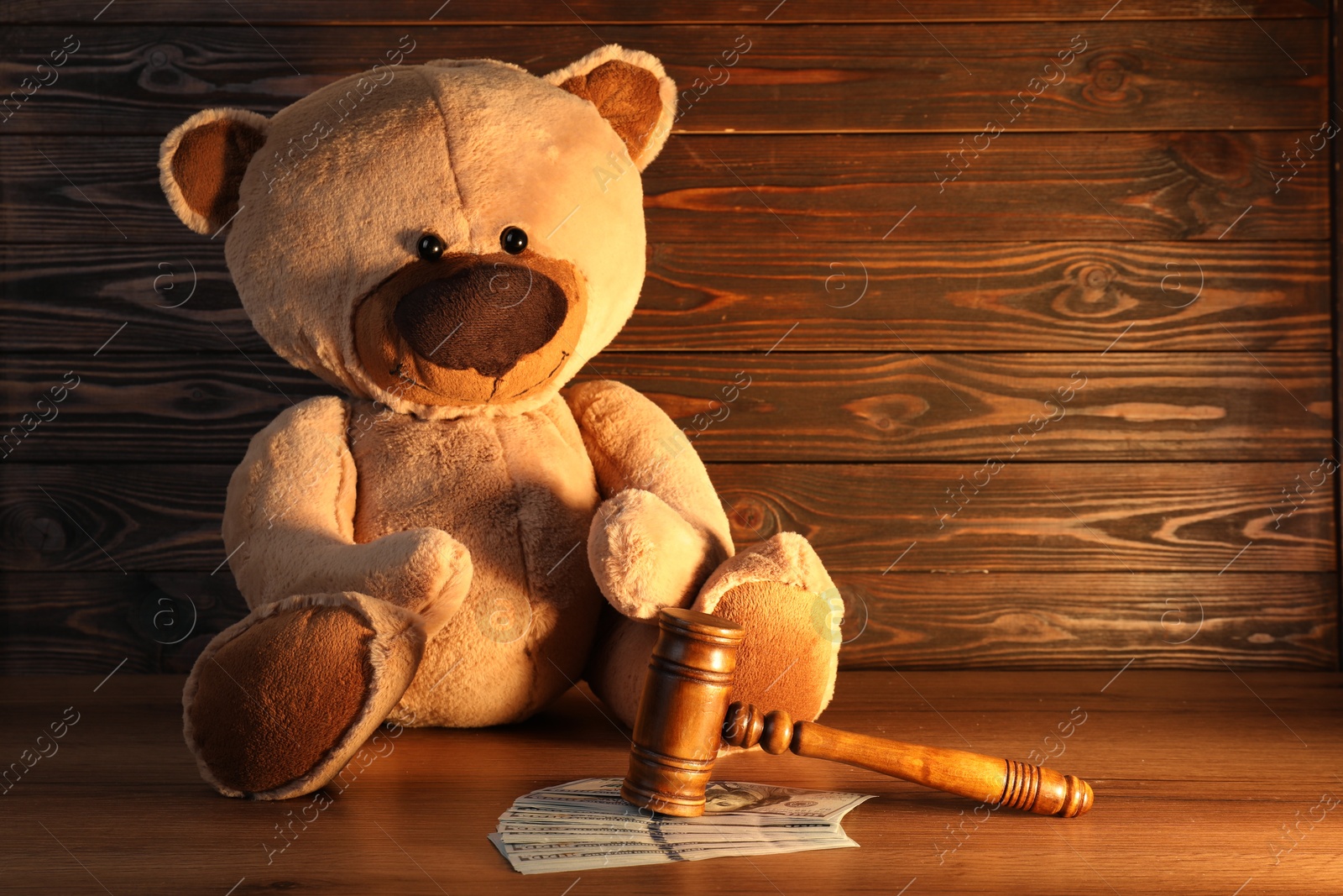 Photo of Alimony. Toy bear, gavel and dollar banknotes on wooden table