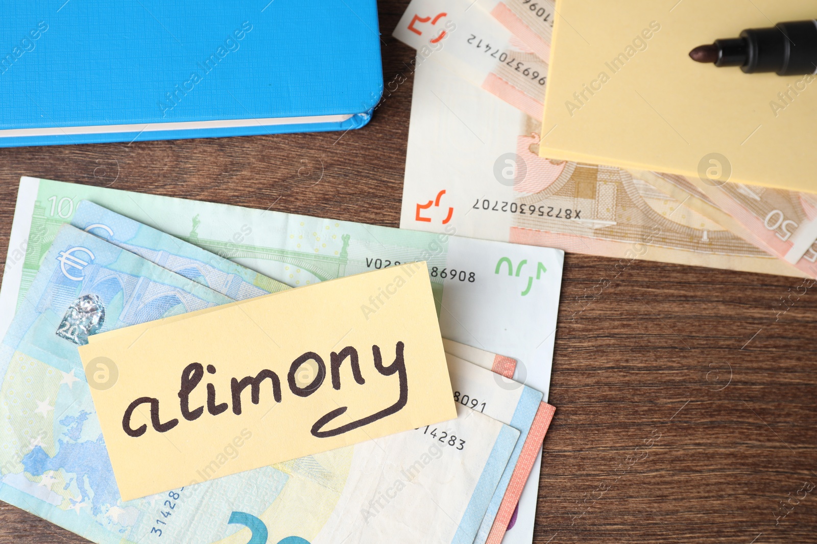 Photo of Card with word Alimony, euro banknotes, felt pen and notebook on wooden table, top view