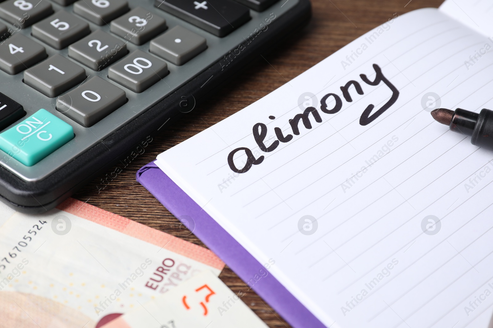 Photo of Notebook with word Alimony, euro banknotes, felt pen and calculator on wooden table, closeup