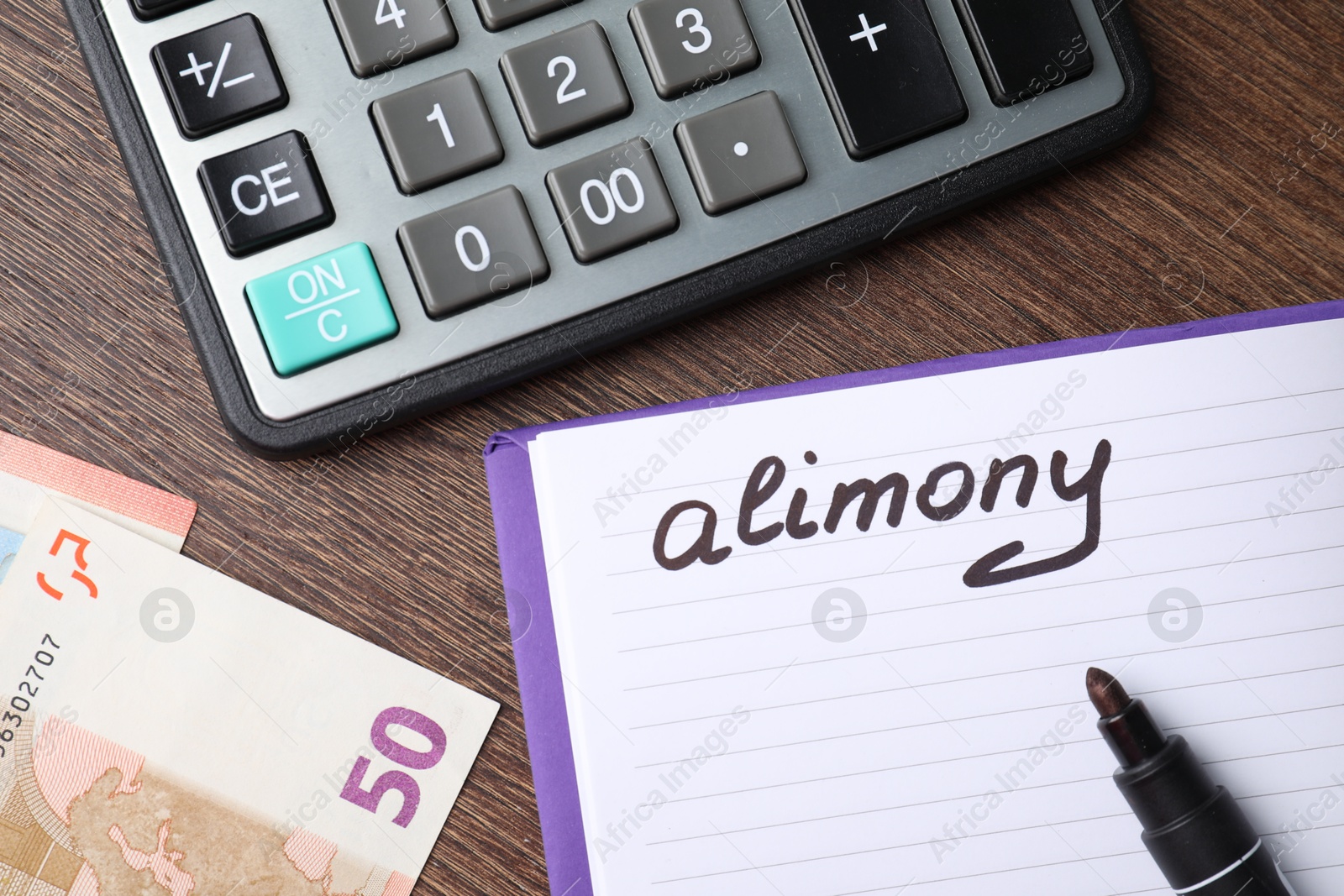 Photo of Notebook with word Alimony, euro banknotes, felt pen and calculator on wooden table, top view