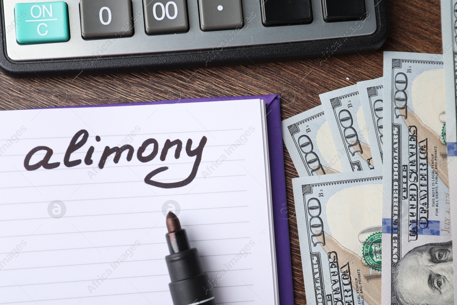 Photo of Notebook with word Alimony, dollar banknotes, felt pen and calculator on wooden table, top view