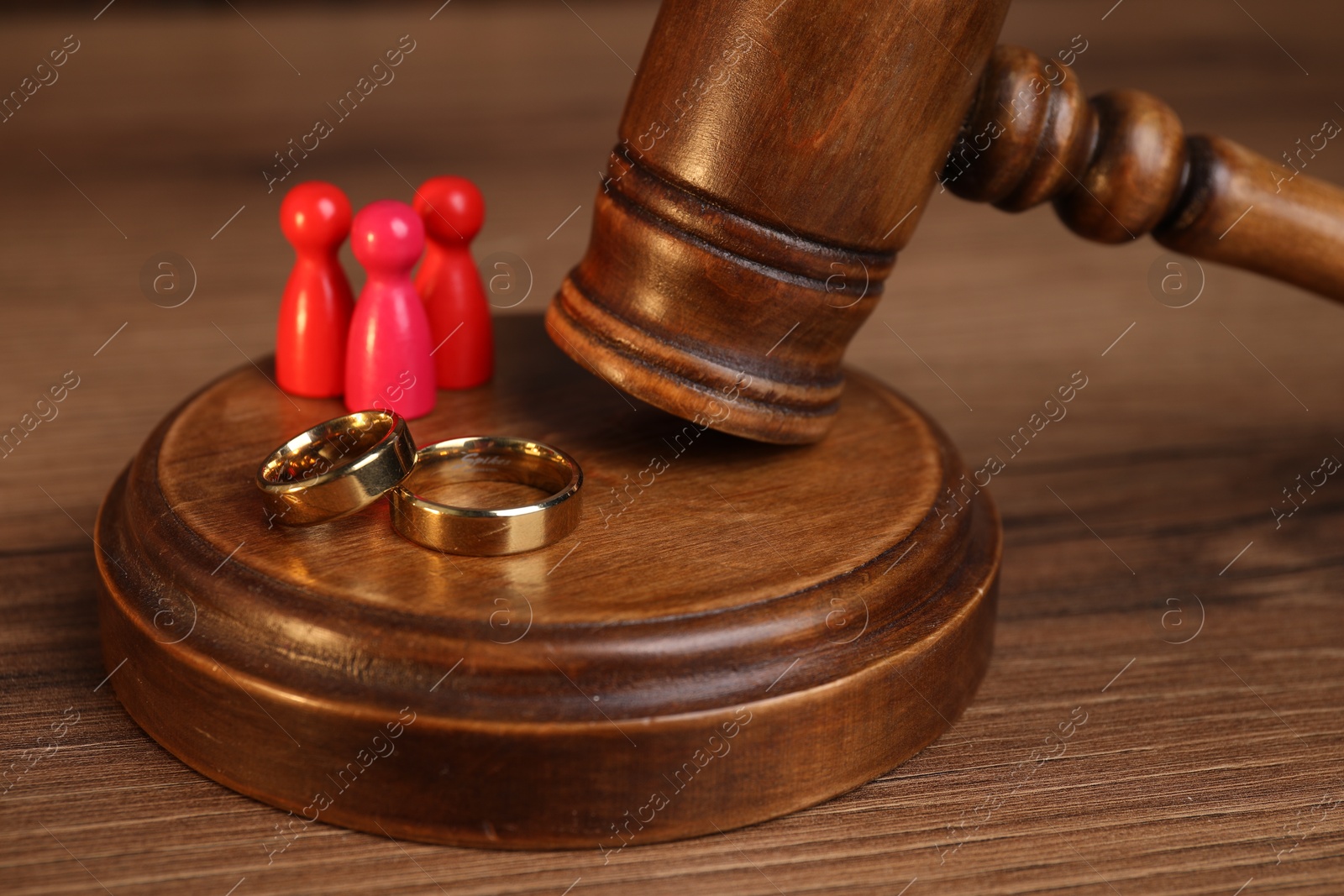 Photo of Alimony. Human figures, gavel and rings on wooden table, closeup