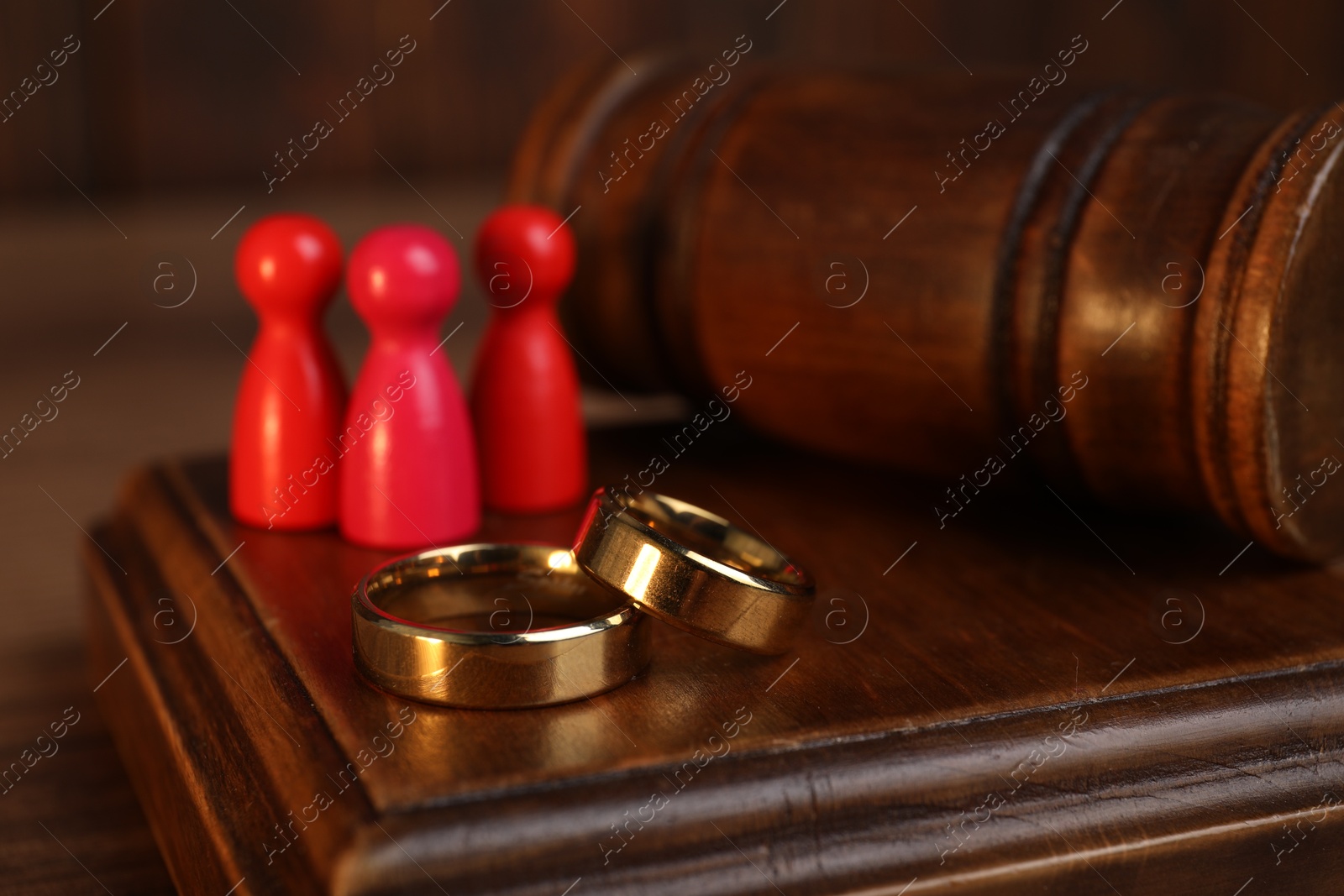 Photo of Alimony. Human figures, gavel and rings on table, closeup