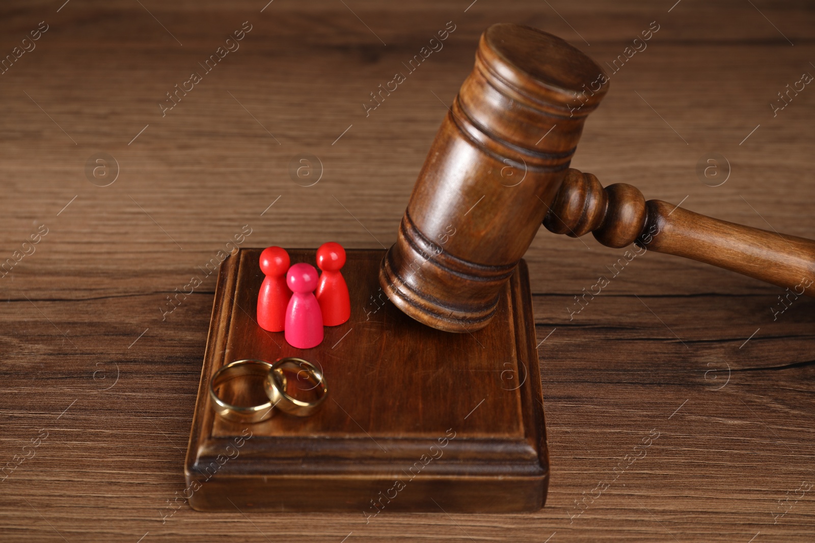 Photo of Alimony. Human figures, gavel and rings on wooden table, closeup