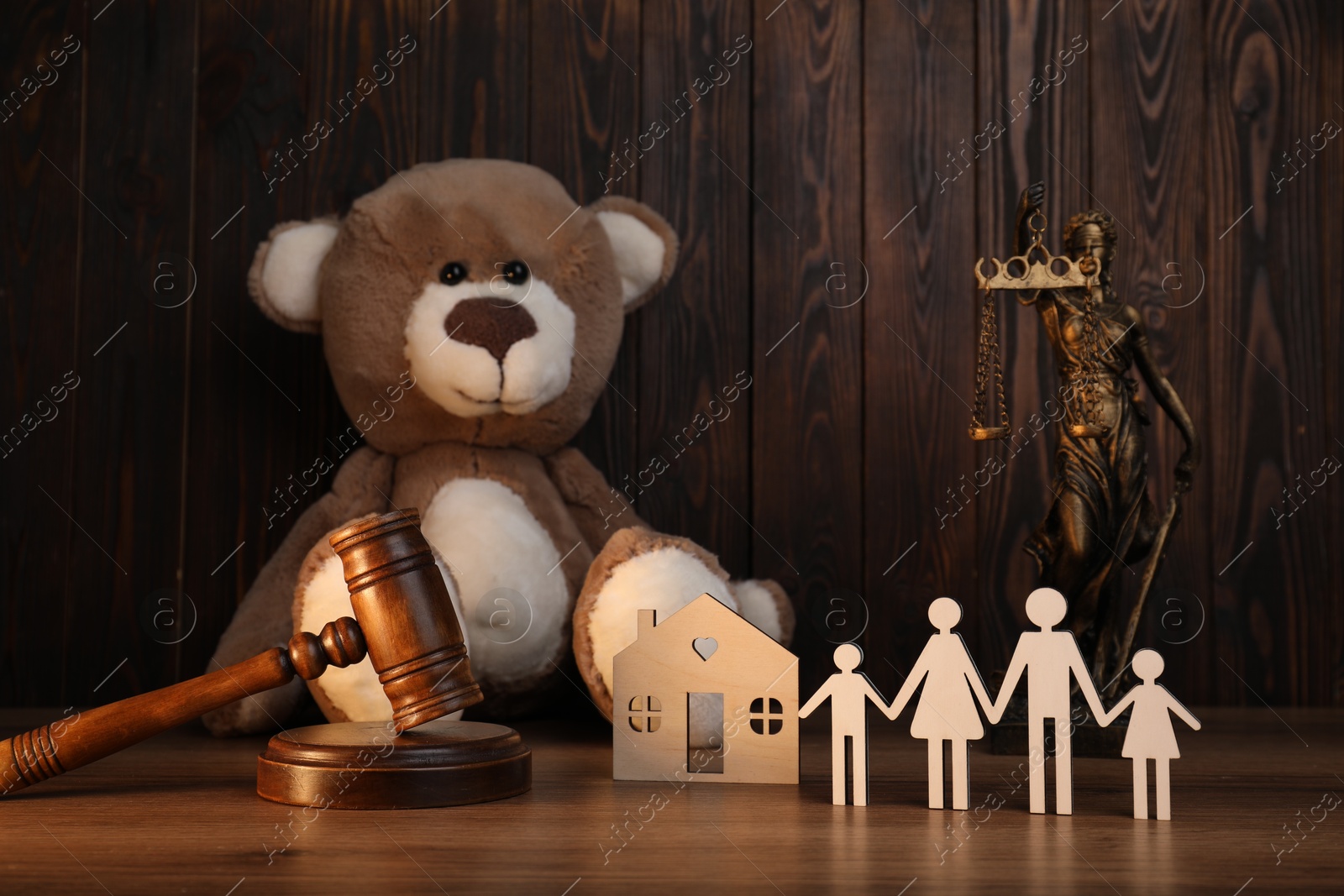 Photo of Alimony. Figures of family, gavel, toy bear, statuette of Lady Justice and house model on wooden table