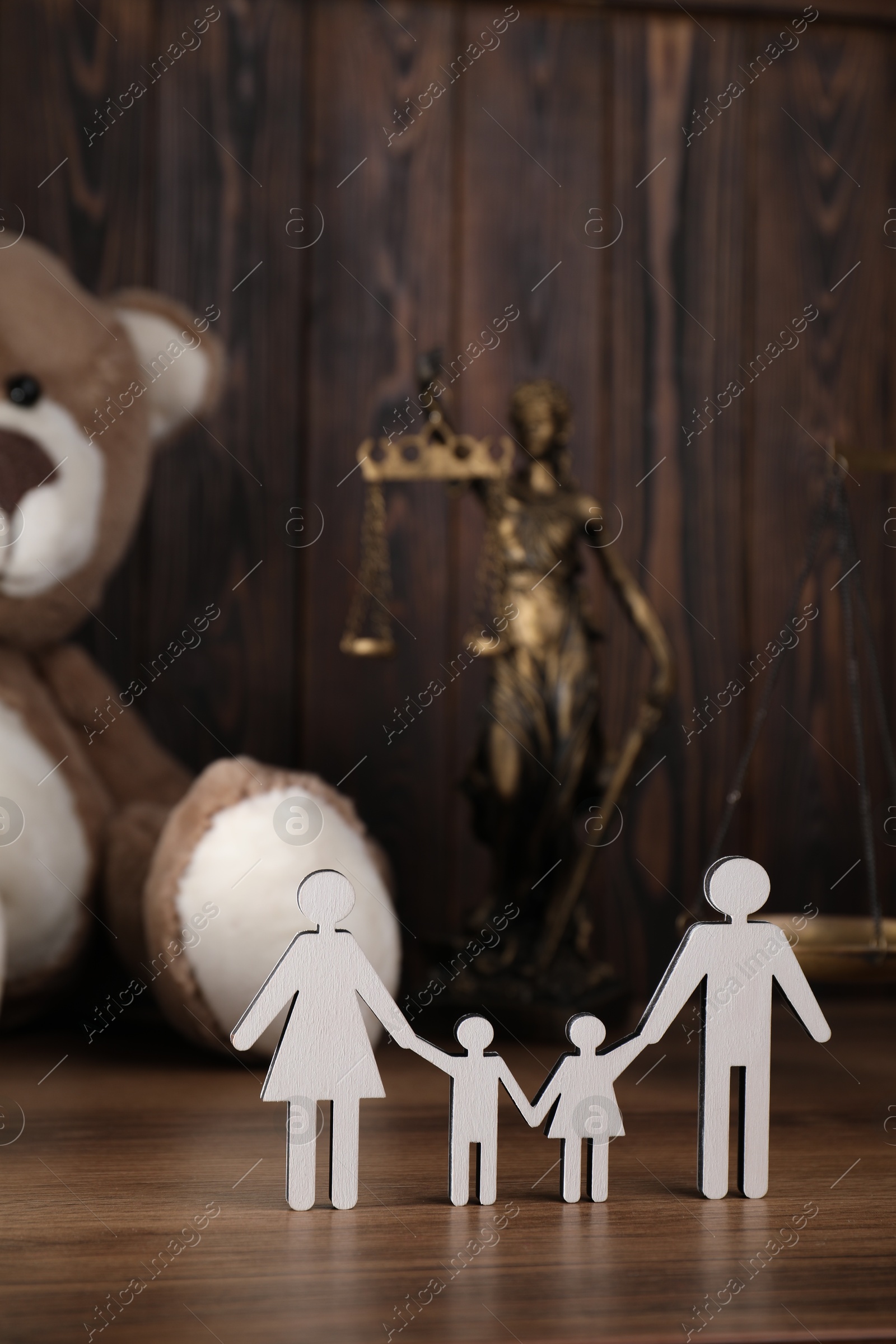 Photo of Alimony. Figures of family, toy bear, statuette of Lady Justice and scales on wooden table