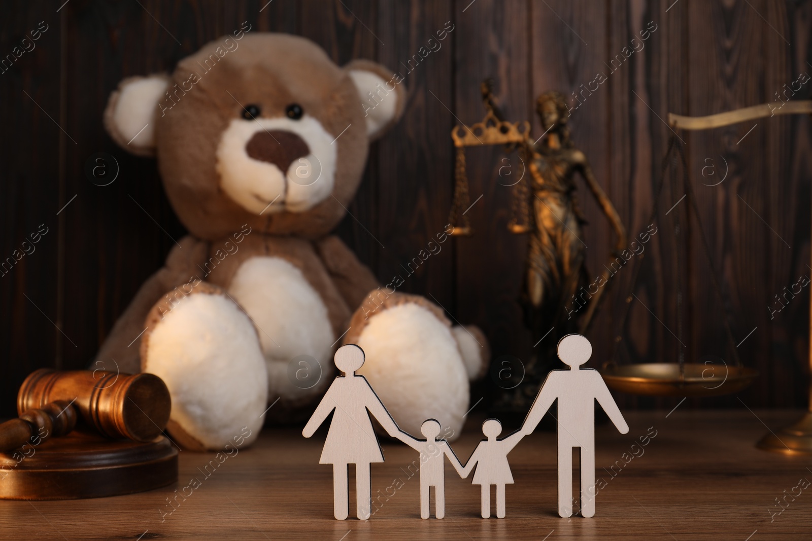 Photo of Alimony. Figures of family, gavel, toy bear, scales and statuette of Lady Justice on wooden table