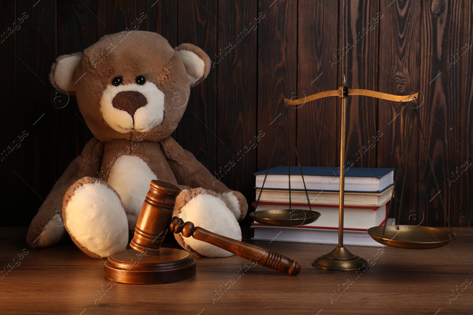 Photo of Alimony. Toy bear, gavel, scales and books on wooden table