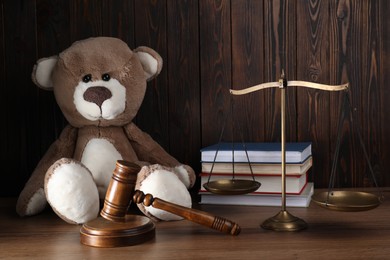 Alimony. Toy bear, gavel, scales and books on wooden table