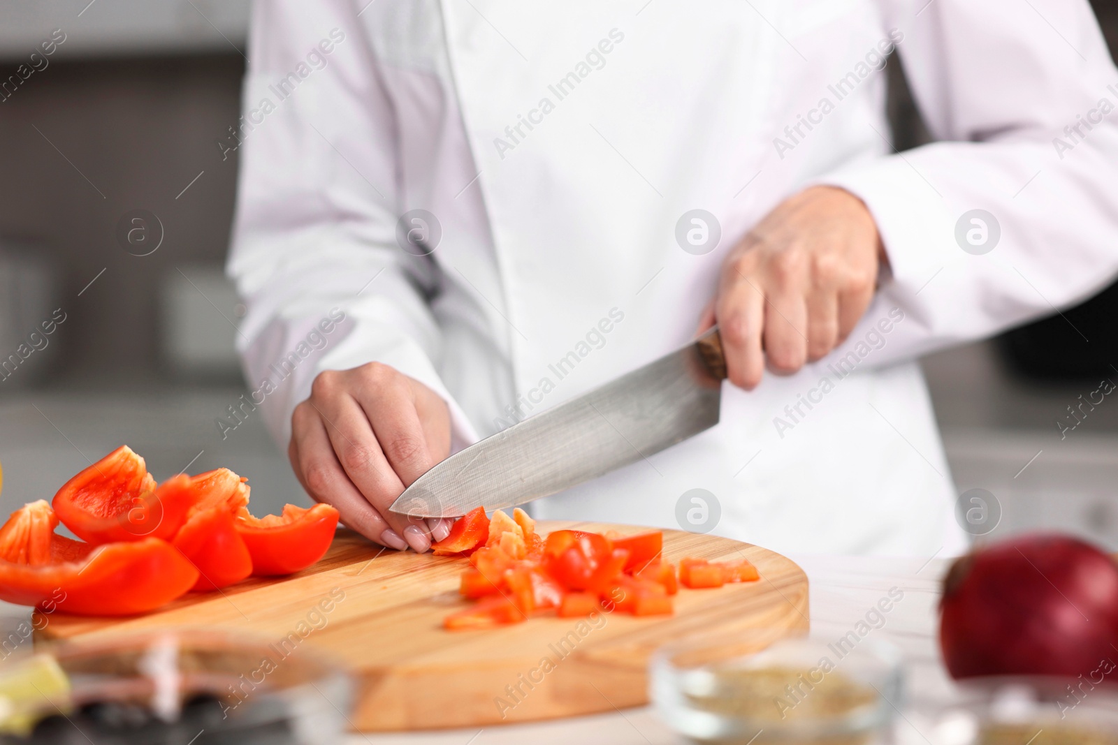 Photo of Professional chef cutting pepper at table in kitchen, closeup