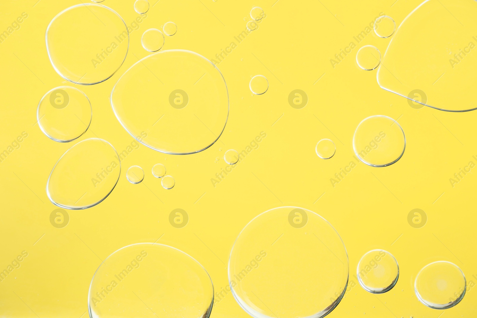 Photo of Sample of cosmetic oil on yellow background, macro view