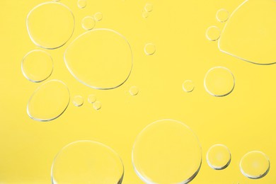 Sample of cosmetic oil on yellow background, macro view