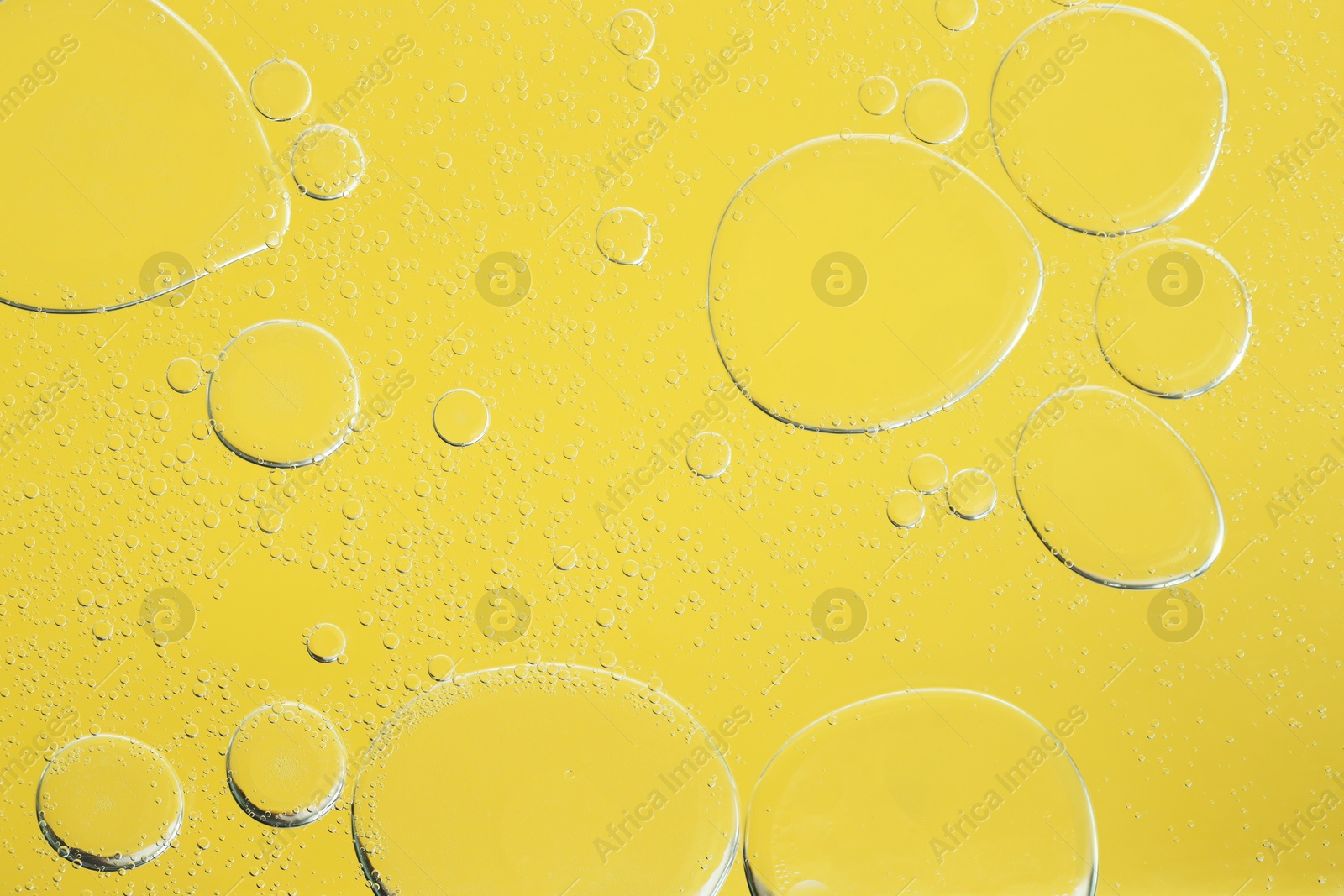 Photo of Sample of cosmetic oil on yellow background, macro view