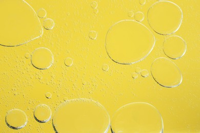 Photo of Sample of cosmetic oil on yellow background, macro view