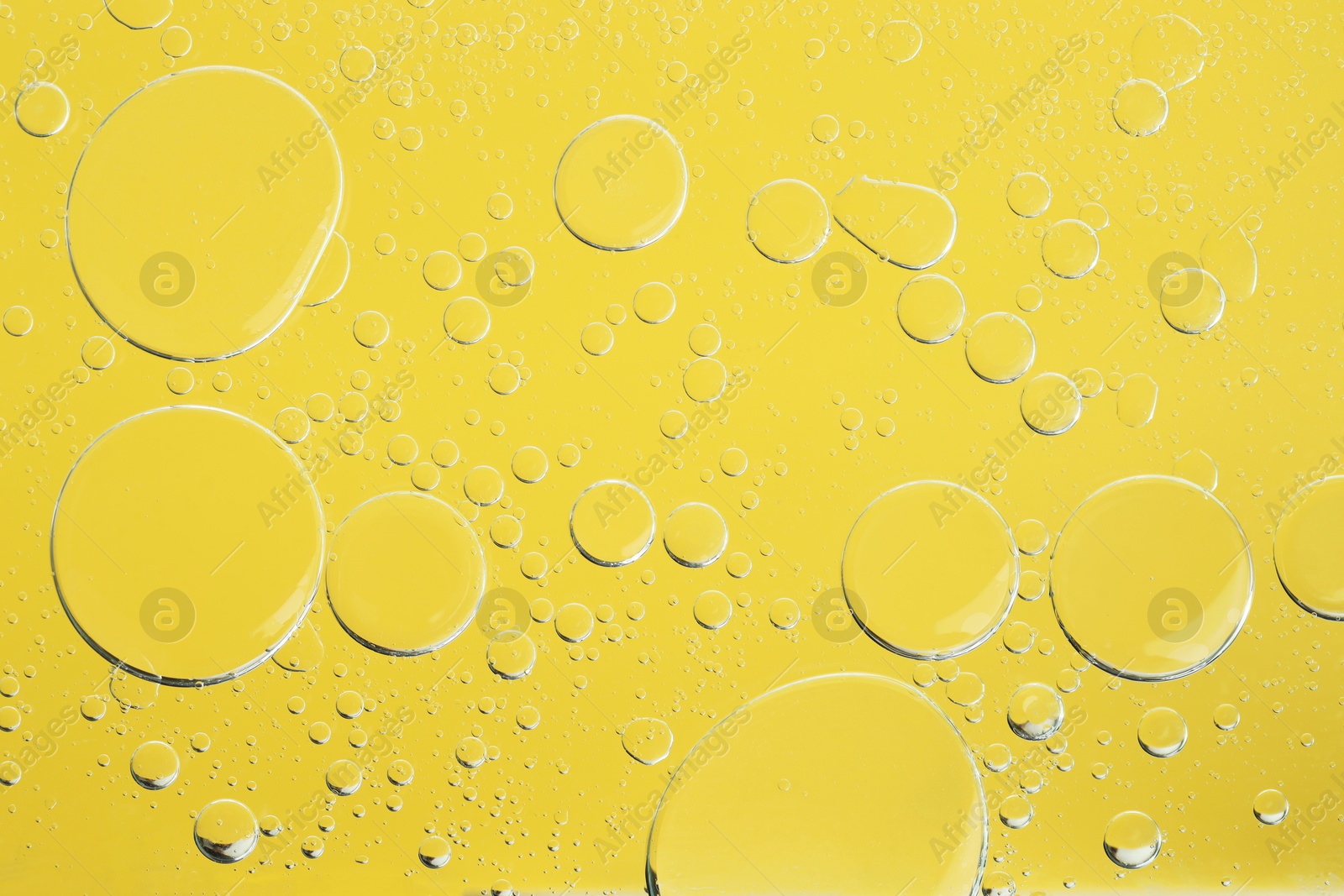 Photo of Sample of cosmetic oil on yellow background, macro view