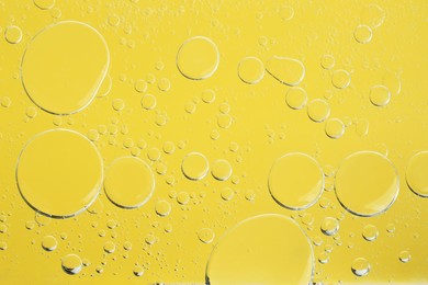 Photo of Sample of cosmetic oil on yellow background, macro view