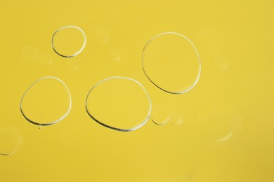 Sample of cosmetic oil on yellow background, macro view