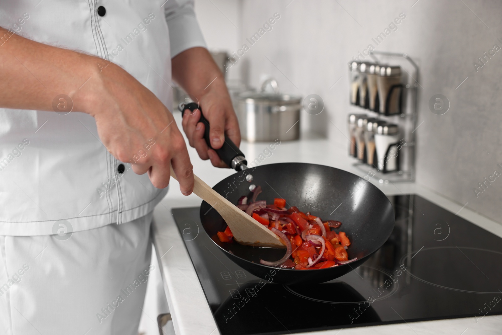 Photo of Professional chef cooking delicious food on stove in kitchen, closeup