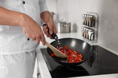 Photo of Professional chef cooking delicious food on stove in kitchen, closeup