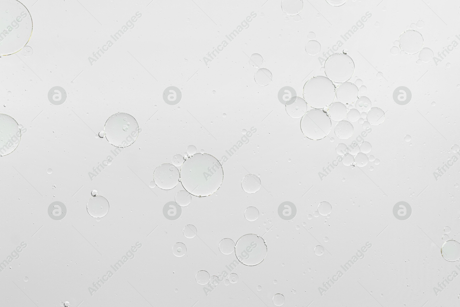 Photo of Essential oil bubbles on white background, macro view. Cosmetic product