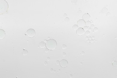 Photo of Essential oil bubbles on white background, macro view. Cosmetic product