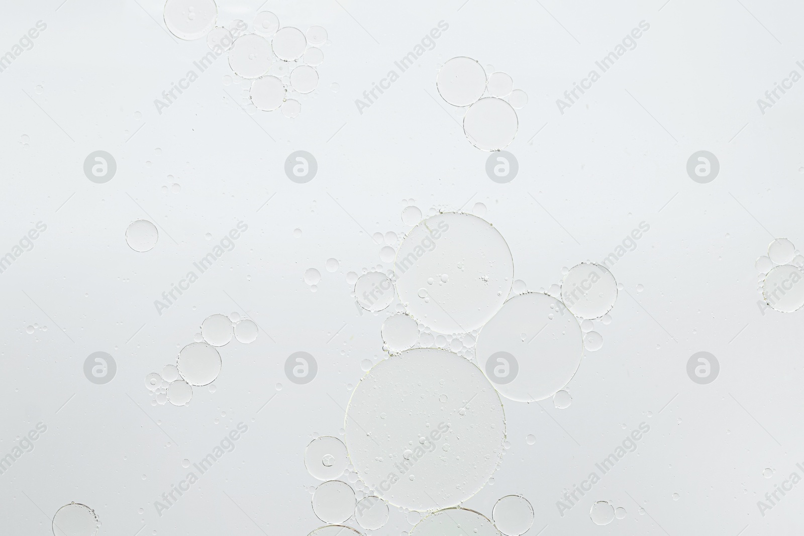 Photo of Essential oil bubbles on white background, macro view. Cosmetic product