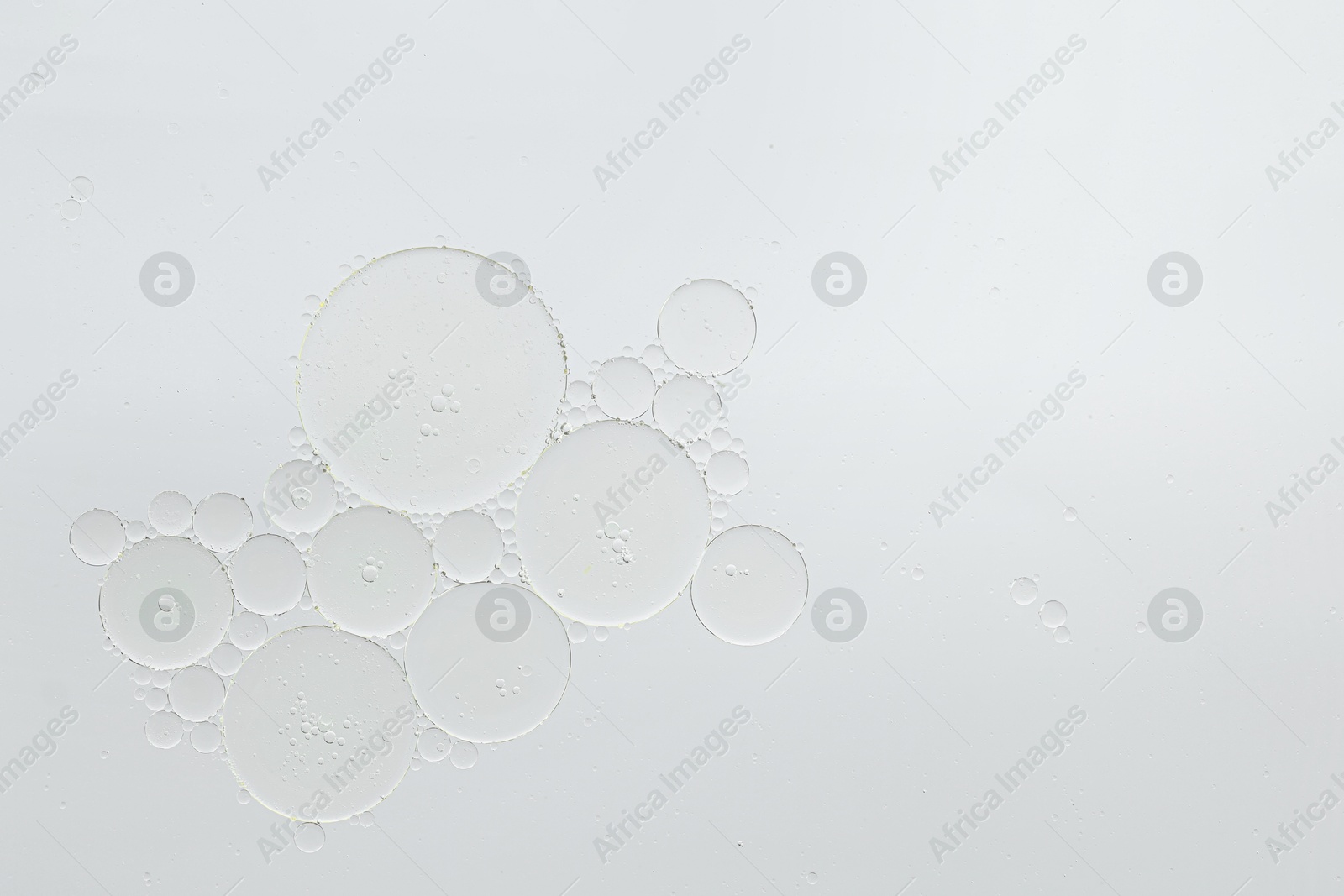 Photo of Cosmetic oil bubbles on white background, macro view. Space for text