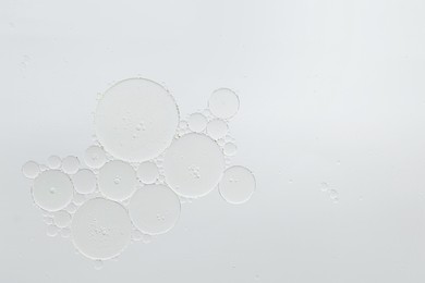 Photo of Cosmetic oil bubbles on white background, macro view. Space for text