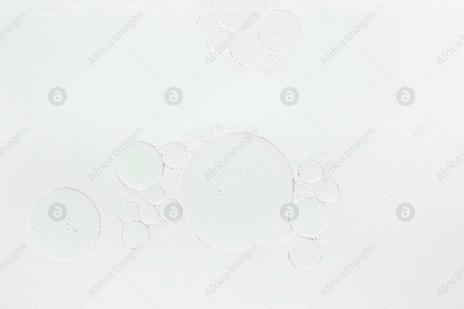 Photo of Essential oil bubbles on white background, macro view. Cosmetic product