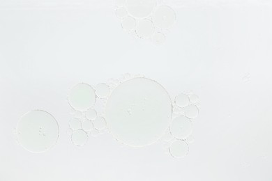 Photo of Essential oil bubbles on white background, macro view. Cosmetic product