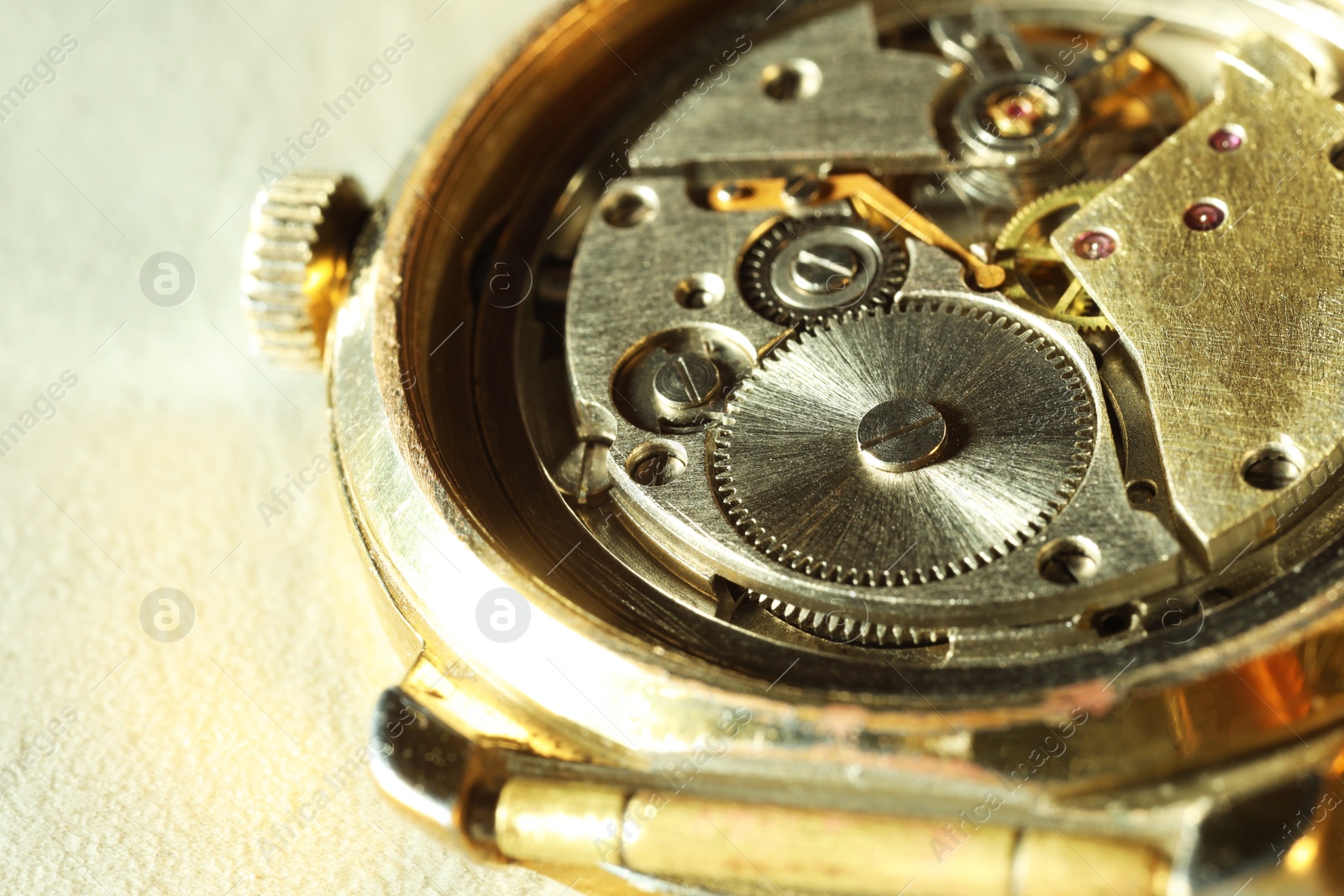 Photo of Mechanism of vintage wrist watch on beige background, closeup