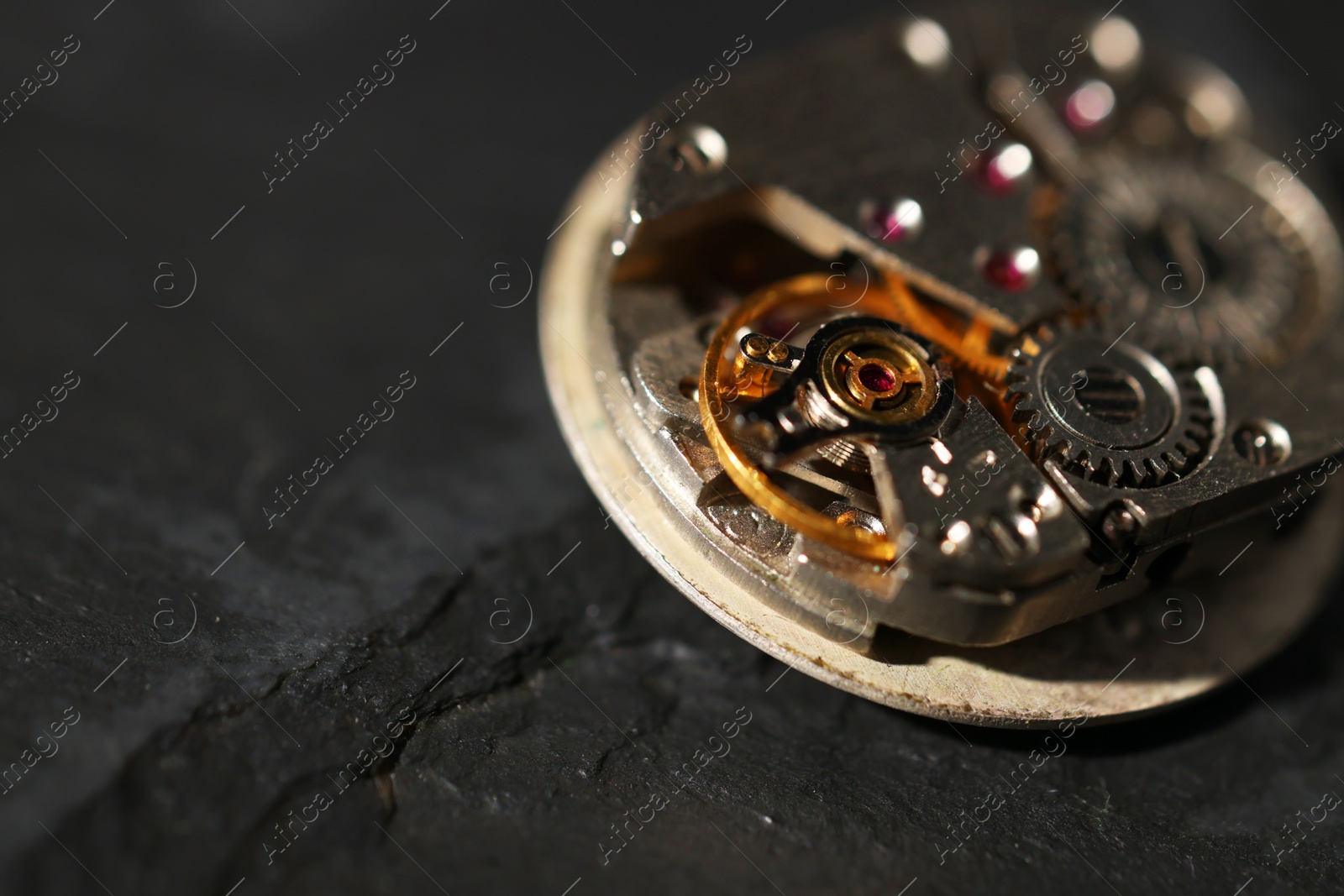 Photo of Mechanism of vintage wrist watch on black table, closeup. Space for text