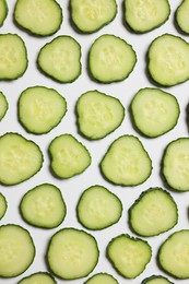 Photo of Slices of fresh cucumbers on white background, flat lay