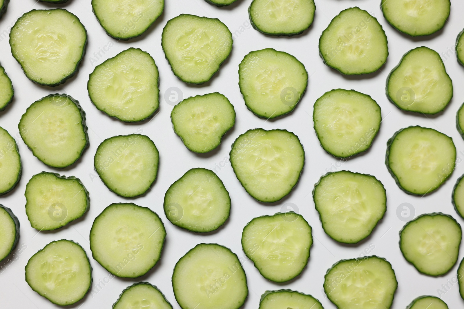 Photo of Slices of fresh cucumbers on white background, flat lay