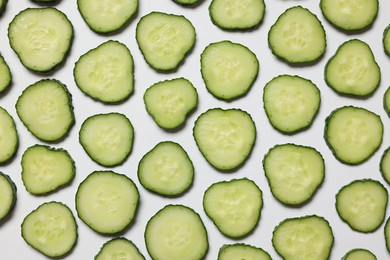 Photo of Slices of fresh cucumbers on white background, flat lay