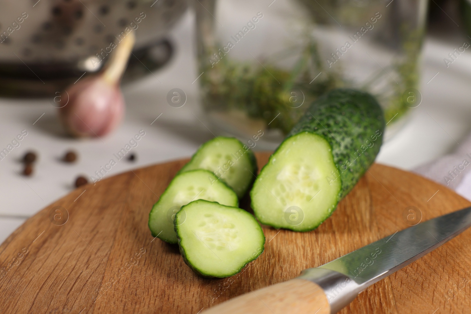 Photo of Board with fresh cut cucumber and knife on light table, closeup