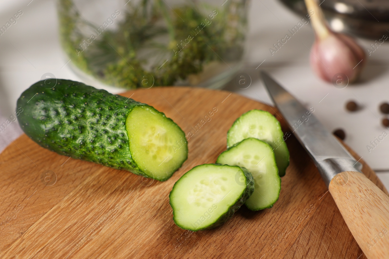 Photo of Board with fresh cut cucumber and knife on light table, closeup